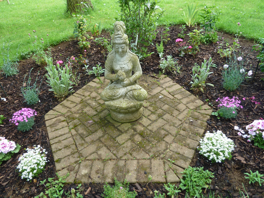Meditative Gartenfigur in gepflegtem Gartenraum