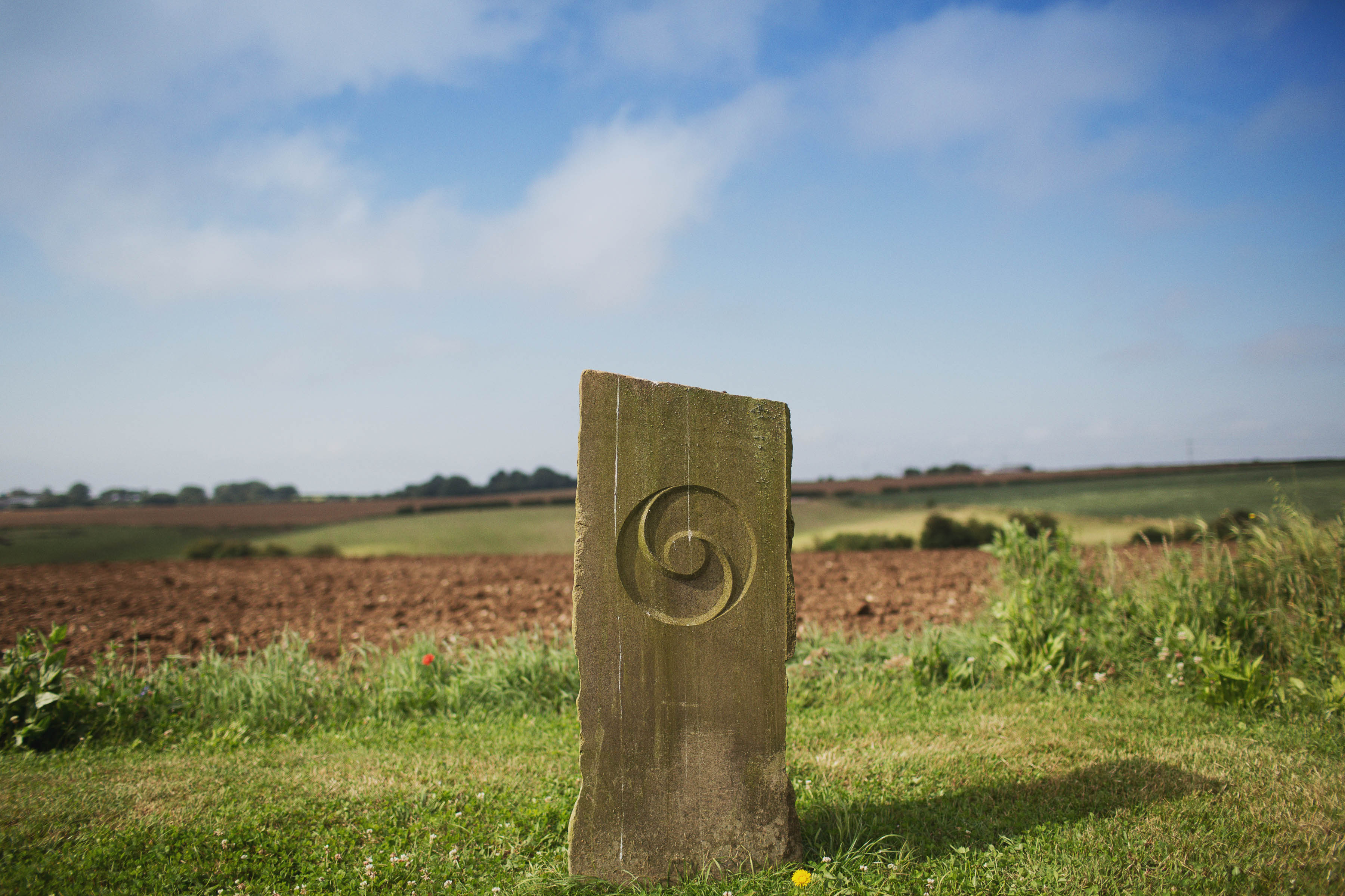 Chakrenweg in offener Landschaft mit steinerner Stele