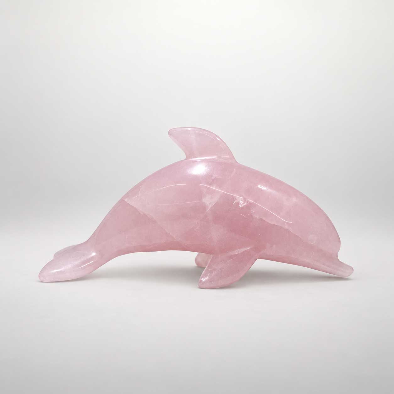 Delfinfigur aus zartrosa Rosenquarz mit natürlichen Steinstrukturen